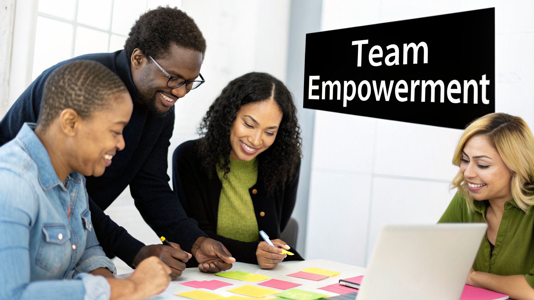 Four diverse colleagues smiling and collaborating around a table with sticky notes, promoting team empowerment.